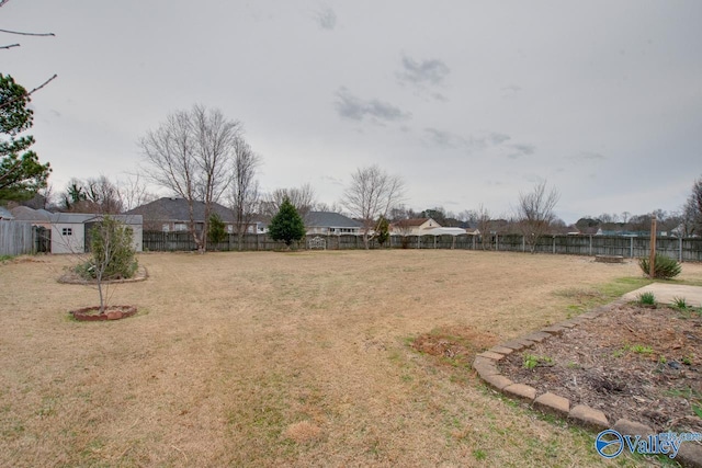 view of yard featuring an outbuilding, a fenced backyard, and a shed