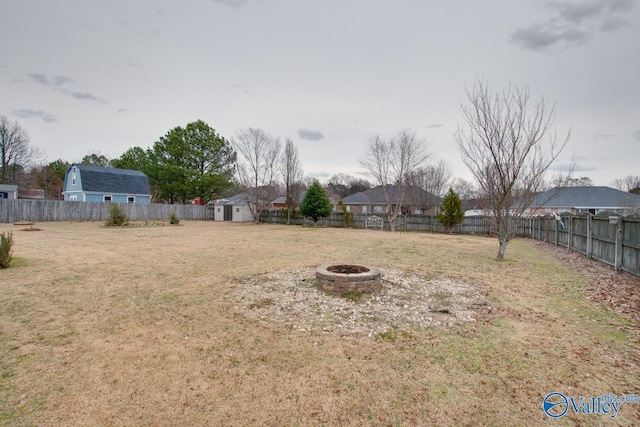 view of yard featuring a fire pit, a storage shed, an outbuilding, and a fenced backyard