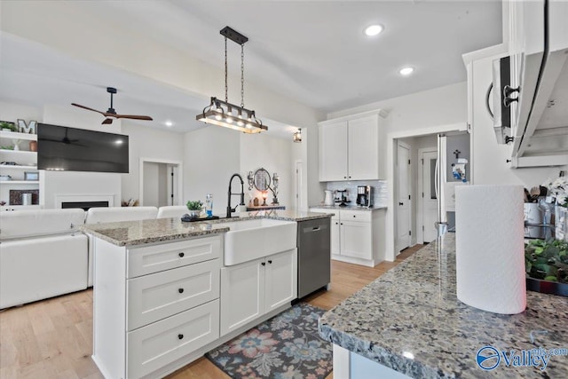 kitchen with white cabinetry, stainless steel dishwasher, a sink, light stone counters, and ceiling fan