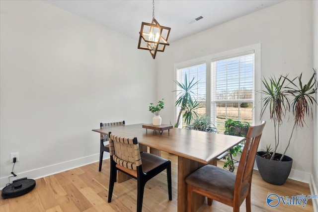 dining area with baseboards, visible vents, a notable chandelier, and light wood-style flooring