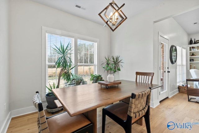 dining area with baseboards, visible vents, an inviting chandelier, and light wood-type flooring