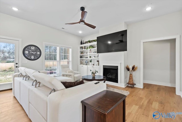 living area with ceiling fan, recessed lighting, a fireplace, and light wood-type flooring