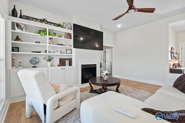 living room featuring baseboards, a fireplace, recessed lighting, a ceiling fan, and light wood-type flooring