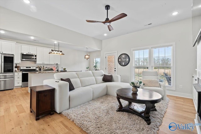 living area featuring baseboards, light wood-type flooring, recessed lighting, and a ceiling fan