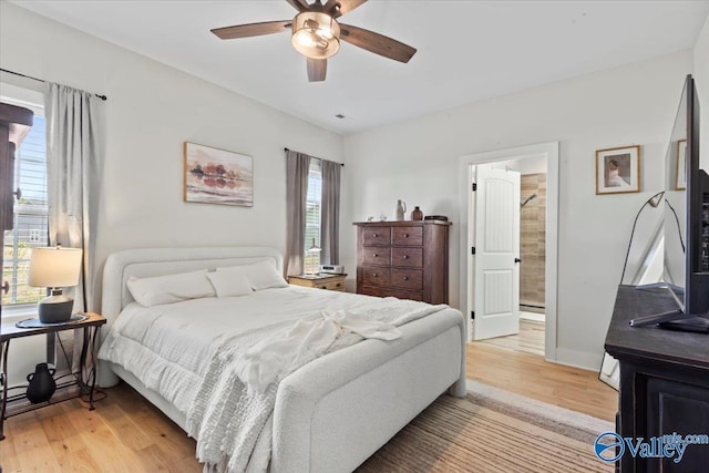 bedroom featuring baseboards, ensuite bath, ceiling fan, and light wood finished floors