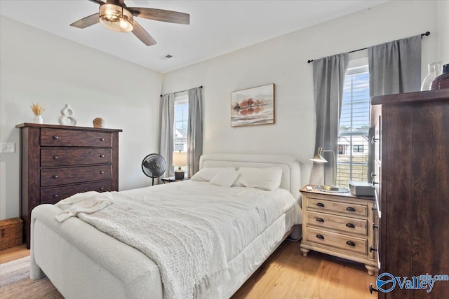 bedroom with ceiling fan, light wood finished floors, and visible vents