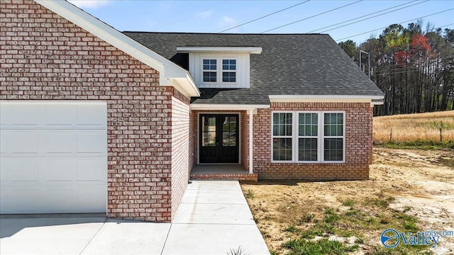 entrance to property featuring french doors, an attached garage, brick siding, and roof with shingles