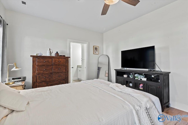bedroom featuring baseboards, ensuite bath, wood finished floors, and a ceiling fan