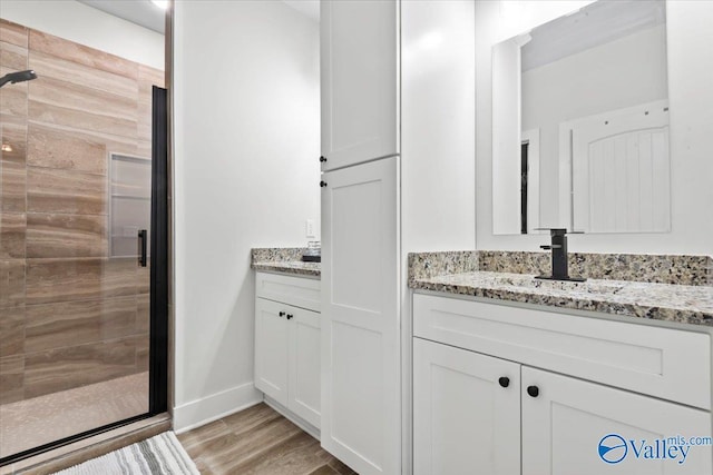 full bath featuring wood finished floors, vanity, baseboards, and a shower stall