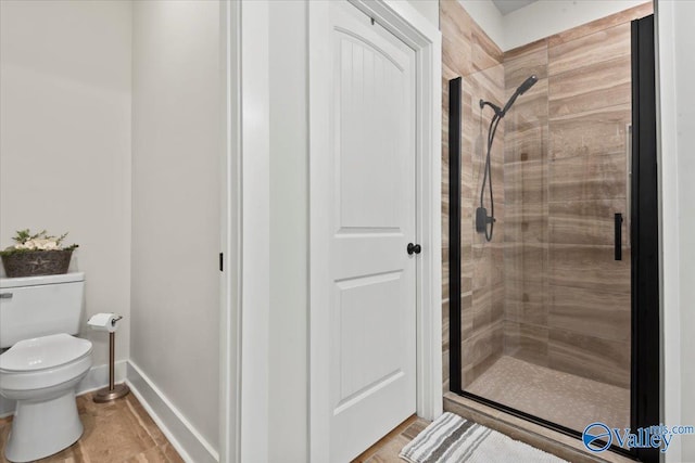 bathroom with toilet, baseboards, and a shower stall