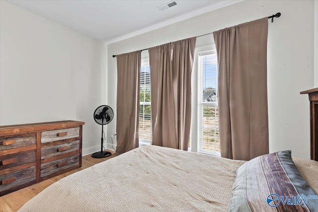 bedroom featuring baseboards, visible vents, and wood finished floors