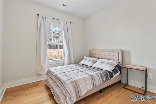 bedroom with visible vents, baseboards, and wood finished floors