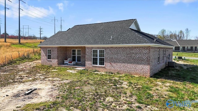 rear view of property with a patio, brick siding, and roof with shingles