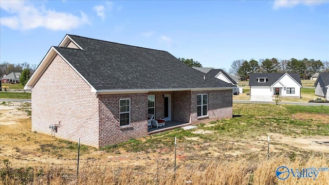 view of front facade featuring brick siding and roof with shingles