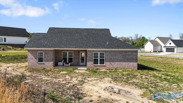 back of property featuring a patio, brick siding, and roof with shingles