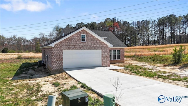 view of front of house featuring brick siding, a garage, driveway, and central AC