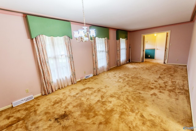 unfurnished dining area with carpet floors, ornamental molding, and a notable chandelier