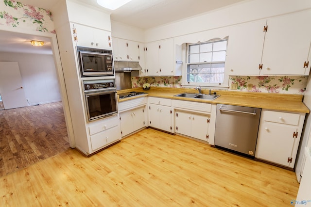 kitchen with sink, white cabinets, stainless steel appliances, and light hardwood / wood-style floors