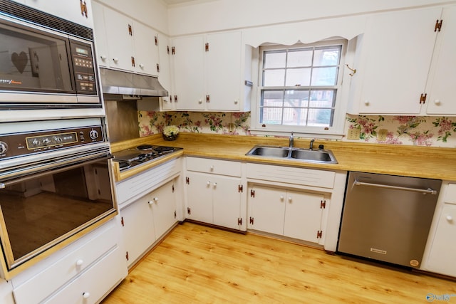 kitchen with sink, white cabinets, light hardwood / wood-style floors, and appliances with stainless steel finishes