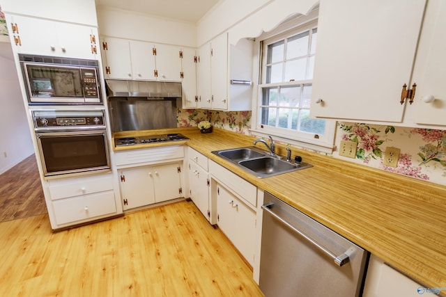 kitchen featuring white cabinets, appliances with stainless steel finishes, light hardwood / wood-style flooring, and sink