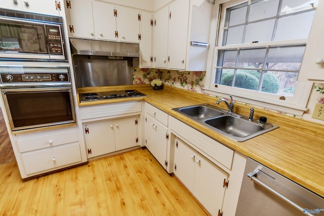 kitchen with white cabinets, light hardwood / wood-style floors, sink, and appliances with stainless steel finishes