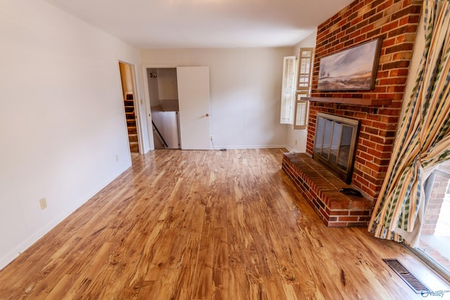 unfurnished living room featuring a brick fireplace and light hardwood / wood-style flooring