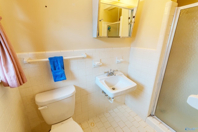 bathroom with sink, tile patterned flooring, an enclosed shower, toilet, and tile walls