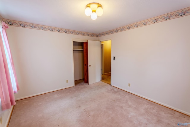 unfurnished bedroom featuring light carpet and a closet