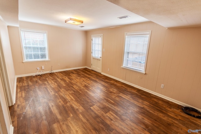 empty room featuring dark wood-type flooring and wood walls