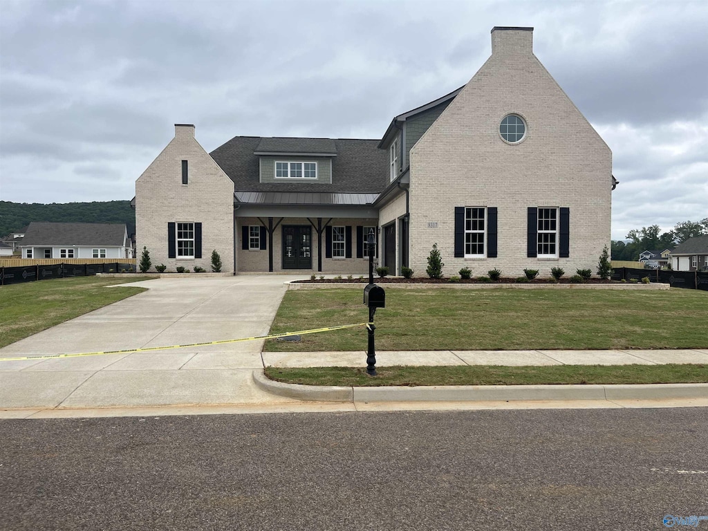 view of front facade featuring a front yard, a chimney, brick siding, and concrete driveway