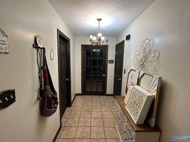 doorway to outside with a notable chandelier, light tile patterned floors, and a textured ceiling