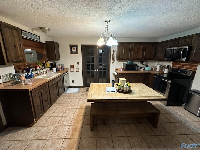 kitchen featuring pendant lighting, black appliances, sink, a textured ceiling, and dark brown cabinets