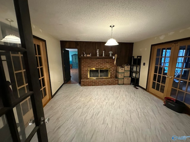 living room featuring a textured ceiling, wood walls, a fireplace, and french doors