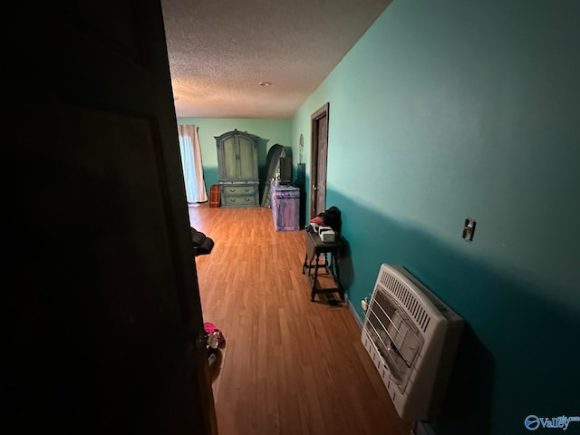 hallway featuring hardwood / wood-style flooring, a textured ceiling, and heating unit