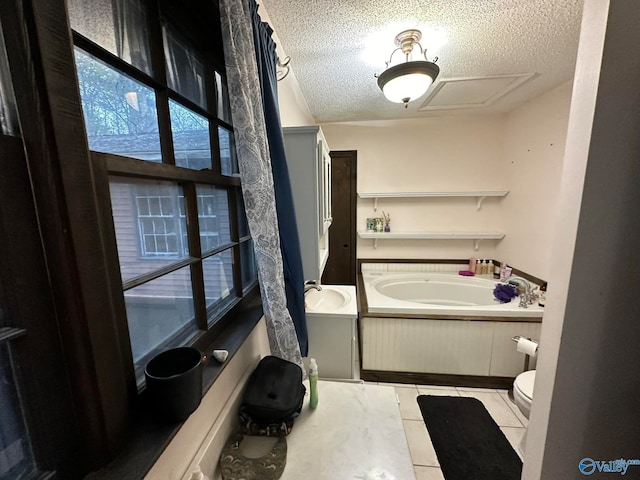 bathroom with a bath, tile patterned floors, sink, toilet, and a textured ceiling