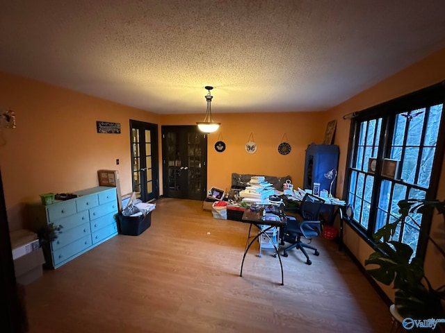 dining area with french doors, wood-type flooring, and a textured ceiling