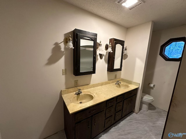 bathroom with vanity, a textured ceiling, and toilet