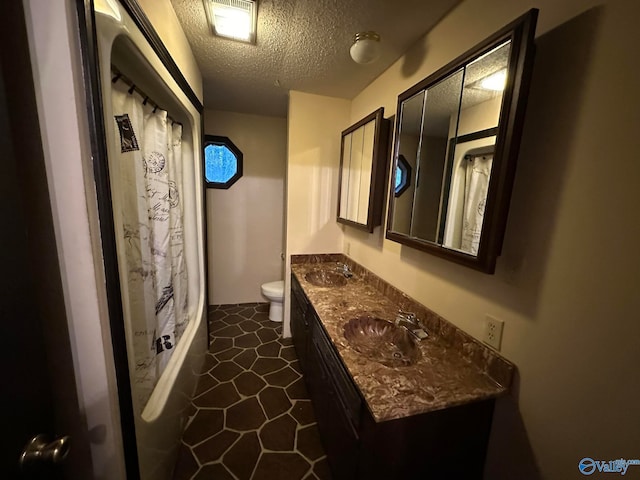 bathroom featuring tile patterned flooring, vanity, a textured ceiling, and toilet