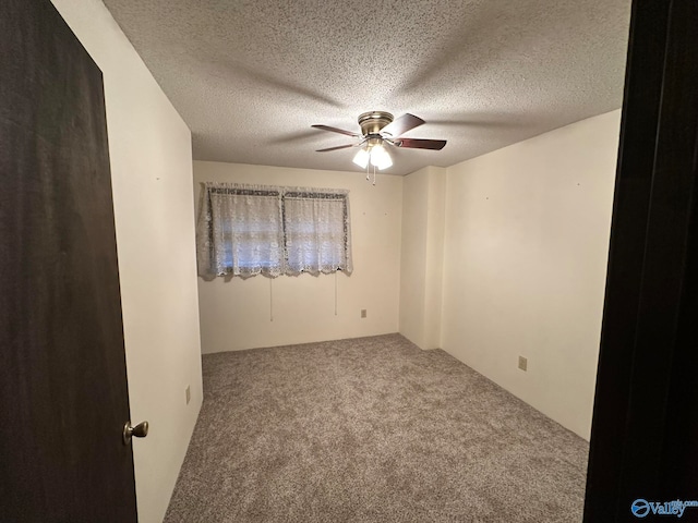 carpeted spare room with ceiling fan and a textured ceiling