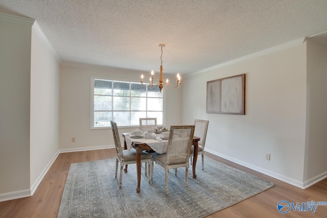 dining space featuring a chandelier, baseboards, wood finished floors, and crown molding