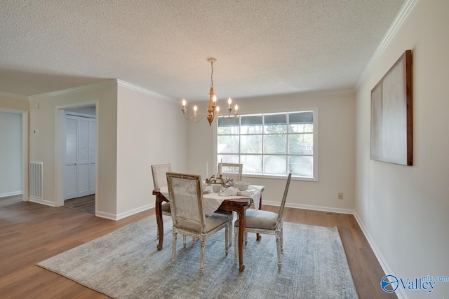 dining space with ornamental molding, a notable chandelier, and wood finished floors