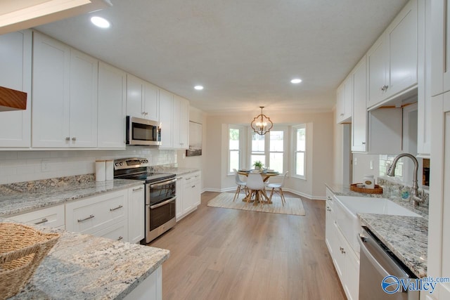 kitchen with appliances with stainless steel finishes, white cabinets, and light stone counters