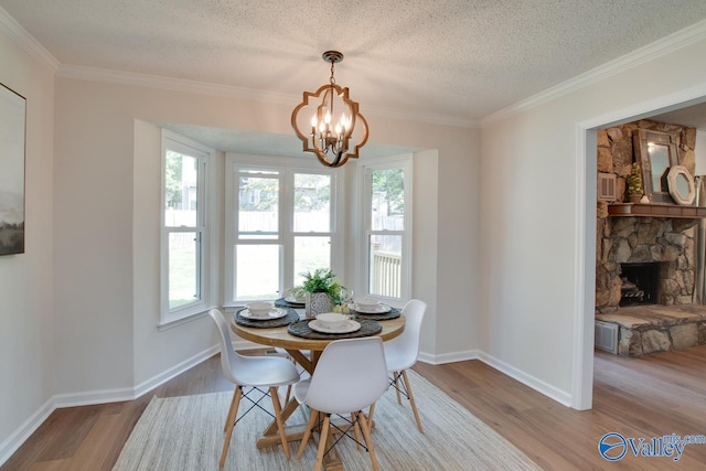 dining room with light wood-style floors, a fireplace, a textured ceiling, and an inviting chandelier