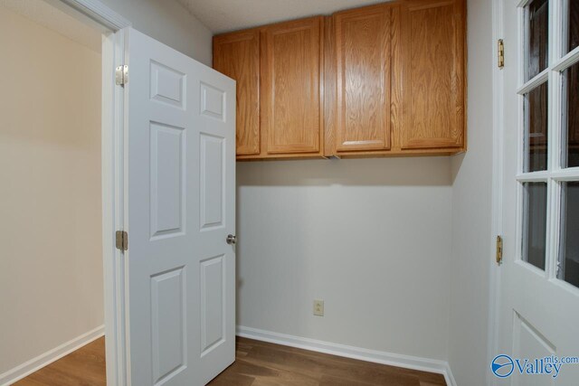 laundry room with dark wood-type flooring and baseboards