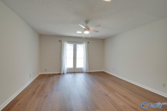 spare room with a textured ceiling, french doors, light wood-style flooring, and baseboards