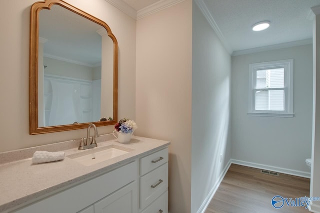 bathroom with baseboards, ornamental molding, wood finished floors, and vanity