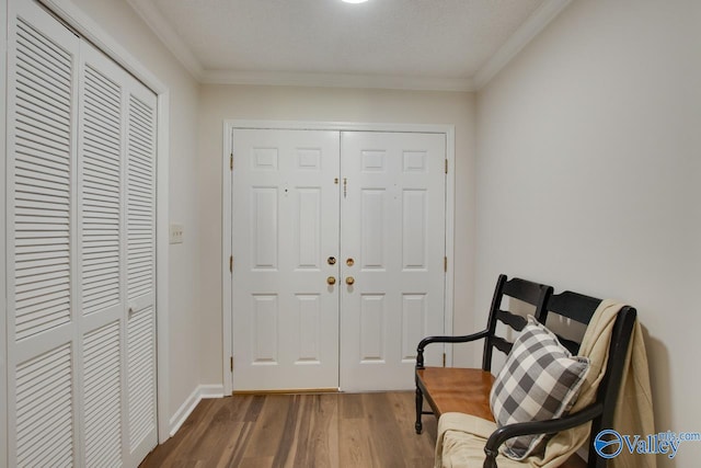 sitting room with baseboards, wood finished floors, and crown molding