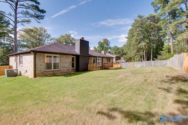 rear view of property featuring brick siding, a chimney, a fenced backyard, and a wooden deck