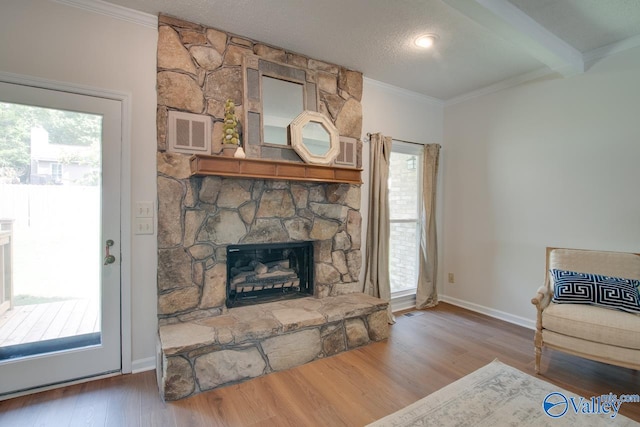 living room with a fireplace, wood finished floors, visible vents, and crown molding