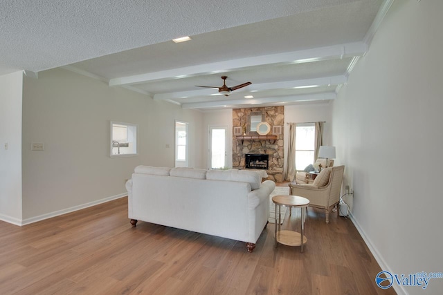 15011 Glory Dr SE, Huntsville, AL 35803 - living area with a healthy amount of sunlight, baseboards, beamed ceiling, ceiling fan, and a stone fireplace